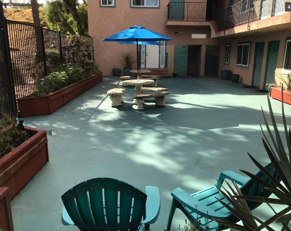 A patio with a table and chairs and an umbrella.